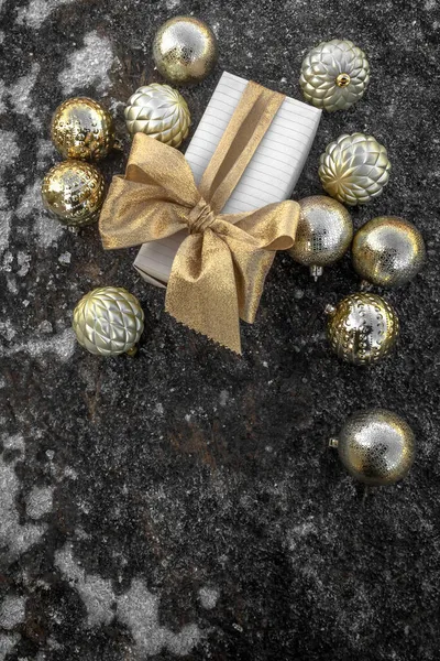 Embalagem festiva decorada com um arco. Perto está um espalhamento de bolas de árvore de Natal em uma superfície gelada. Conceito: celebração do Natal e Ano Novo, loja de presentes, decorações de Natal. — Fotografia de Stock
