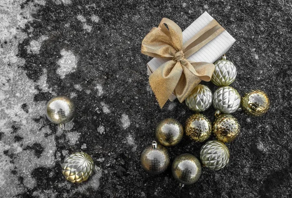 Embalagem festiva decorada com um arco. Perto está um espalhamento de bolas de árvore de Natal em uma superfície gelada. Conceito: celebração do Natal e Ano Novo, decorações de Natal. — Fotografia de Stock