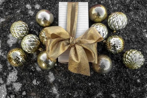 Embalagem festiva decorada com um arco. Perto está um espalhamento de bolas de árvore de Natal em uma superfície gelada. Conceito: celebração do Natal e Ano Novo, decorações de Natal. — Fotografia de Stock