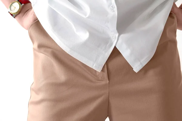 一个白色的女人站在前面，双手放在臀上，穿着一件白色衬衫和米色的裤子。概念：服装规范、经典、女商人、办公室职员、时尚与潮流、时尚. — 图库照片
