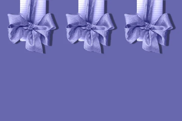 Gifts, knotted in a bow, painted in the color of the year veri peri. Located at the top, cropped. Space for text. Concept: holiday and celebration, Christmas and New Year, fashion and trends.