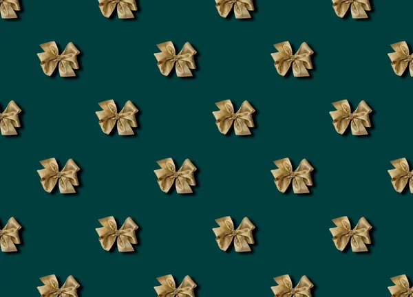 Gouden strik voor het decoreren van geschenken op een groene achtergrond. Prachtig gebonden strik. Foto van een cadeaupakket met een naadloos patroon. — Stockfoto