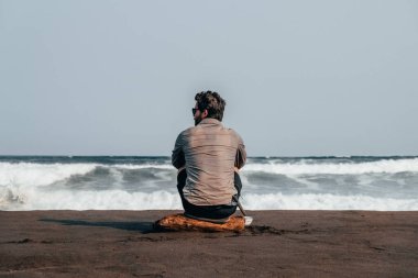 Yalnız adam sahilde Pasifik Okyanusunu izliyor..