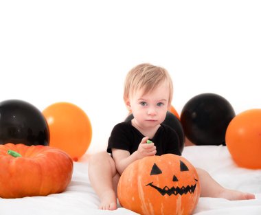 Şirin, korkmuş beyaz bir kız bebek. 1 yaşında, beyaz arka planda yatağında, kameraya bakıyor. Evde sevimli bir bebek ya da Cadılar Bayramı partisinde çocuk korkusu..