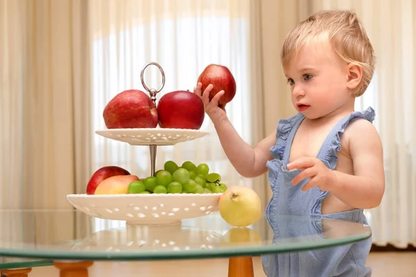 금발의 금발의 아기가 과일을 그릇을 바라보고 있습니다 아이들을 건강하고 맛있는 — 스톡 사진