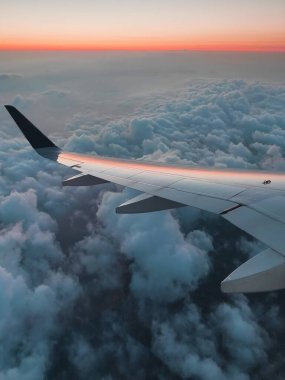 Güzel turuncu gündoğumu sabah mavi bulutların altında ve uçağın penceresinde. Muhteşem gökyüzü ve güneş ışığı. Dikey fotoğraf. Uçak ya da konserle seyahat.