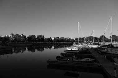 Tekneli küçük bir limanın siyah beyaz fotoğrafı.