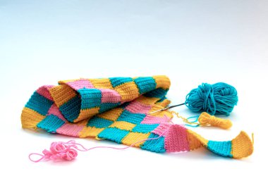 Üretim aşamasında çok renkli örgü şeyler. Evde yapılan şeyler. El yapımı eşyalar, örgü iğneleri, yün iplikler, beyaz arka plan, beyaz arka plan.
