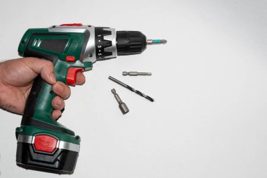 Matkap şarj edilebilir, işe başlamadan önce elinde. Bir tornavidayla, haç sopasıyla çalışıyor..