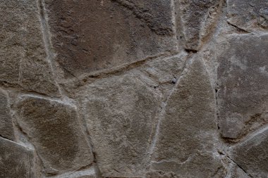 Arka plan ham, vahşi taştan yapılmış, inanılmaz bir dokusu var. Vahşi taşın eski ustaları tarafından yapılmış, muhteşem bir deseni olan taş bir duvar. Taş bloklardan yapılmış eski bir binanın desenli duvarı..