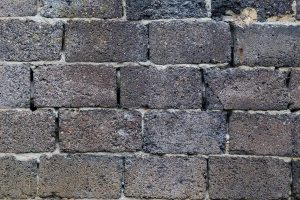 Arka plan beton harçla yapıştırılmış taş bloklardan yapılmış dokulu bir duvar. Eski bir duvarın dokusu. Zamandan ve sert havadan dökülüyor..