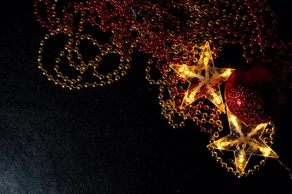 Siyah arkaplanda altın ve kırmızı boncuklar ve beş köşeli yıldızlar. Siyah arka planda iki altın yıldız ve Noel süslemeleri, fotokopi alanı da var. Mutlu Noeller ve mutlu yıllar..