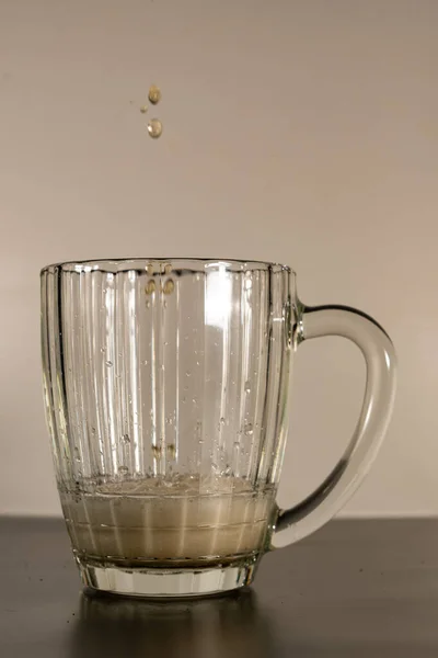 Beer mug filled with foamy, light beer. The glass is slightly filled with beer and foam. On the eve of a beer party and watching football.