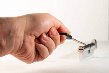 Elinin parmaklarında, anahtar deliğini gösteren düz bir anahtar. Anahtar deliği, larva, düz tuş ve avuç içi, arka planda açık renk..