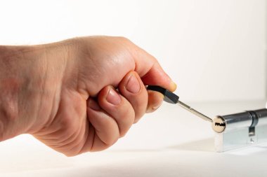 Elin parmaklarında, anahtar deliğine yerleştirilmiş düz bir anahtar. Anahtar deliği, larva, düz tuş ve avuç içi, arka planda açık renk..