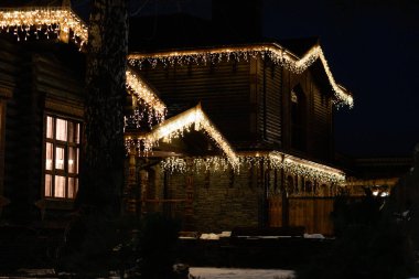 Gece, ev bir çelenkle süslenir, bayram arifesinde. Yılbaşı arifesinde ve Noel arifesinde ev aydınlatmayla süslenmişti..