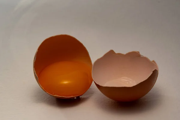 Kahverengi tavuk yumurtasının iki yarısı, içi boş ve sarısı da var. Kabuğun iki yarısı, yumurta sarısının bir yarısında, arka planda, Paskalya arifesinde..