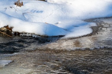 Karla kaplı kıyılar, fırtınalı bir nehirde buz ve su. Fırtınalı bir dağ nehrinde buz, kar ve fırtınalı bir nehirde buz açıldı..