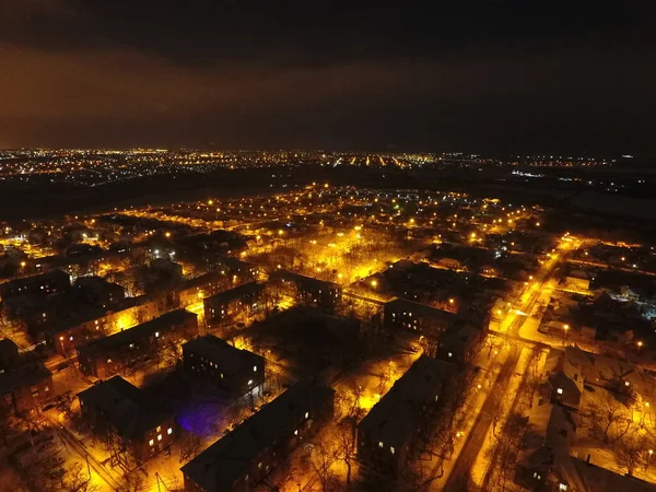 Kar ve ışıklarla dolu bir gece şehri. Gökyüzünde ay ve bulutlar var. Sarı benekli fenerlerle kaplı karla kaplı sokaklar. Mariupol