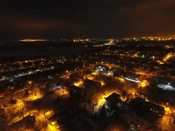 Kar ve ışıklarla dolu bir gece şehri. Gökyüzünde ay ve bulutlar var. Sarı benekli fenerlerle kaplı karla kaplı sokaklar. Mariupol
