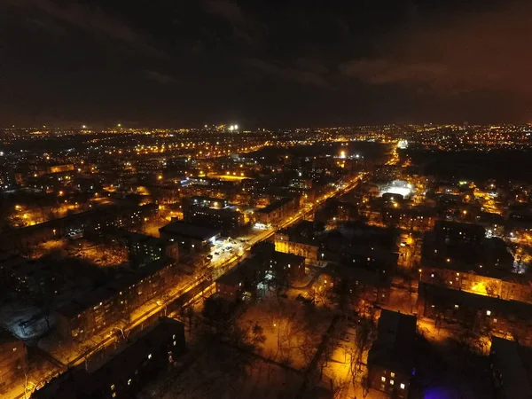 Kar ve ışıklarla dolu bir gece şehri. Gökyüzünde ay ve bulutlar var. Sarı benekli fenerlerle kaplı karla kaplı sokaklar. Mariupol