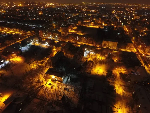 Нічне місто в снігу і вогні. На небі є місяць і хмари. Вкриті снігом вулиці з плямистими ліхтарями. Маріуполь — стокове фото