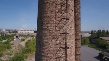 İnsansız hava aracının görüntüsü. Fabrika borusu boyunca yükseldi. Arka plandaki fabrikaların kalıntıları.