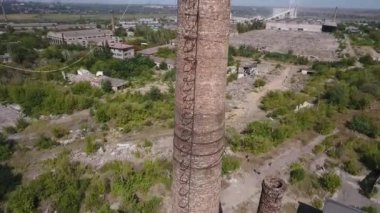 İnsansız hava aracının görüntüsü. Fabrika borusundan aşağı inin. Arka plandaki fabrikaların kalıntıları.