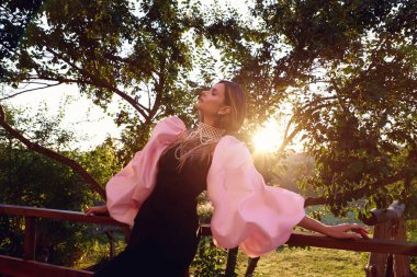 Güzel bir kadın lavanta tarlasında gün batımında siyah ve pembe elbiseler içinde dinleniyor. Çiçek tarlasındaki sarışın kadın. Provence.