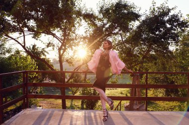 Güzel bir kadın lavanta tarlasında gün batımında siyah ve pembe elbiseler içinde dinleniyor. Çiçek tarlasındaki sarışın kadın. Provence.