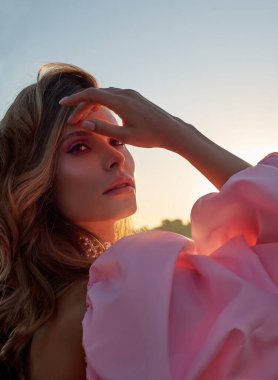 Güzel bir kadın lavanta tarlasında gün batımında siyah ve pembe elbiseler içinde dinleniyor. Çiçek tarlasındaki sarışın kadın. Provence.