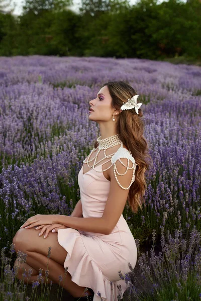 Güzel bir kadın lavanta tarlasında gün batımında siyah ve pembe elbiseler içinde dinleniyor. Çiçek tarlasındaki sarışın kadın. Provence.