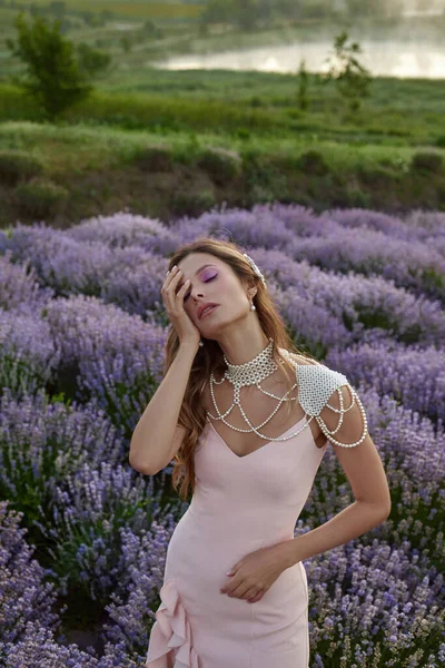 Güzel bir kadın lavanta tarlasında gün batımında siyah ve pembe elbiseler içinde dinleniyor. Çiçek tarlasındaki sarışın kadın. Provence.