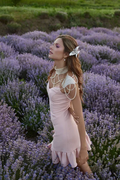 Güzel bir kadın lavanta tarlasında gün batımında siyah ve pembe elbiseler içinde dinleniyor. Çiçek tarlasındaki sarışın kadın. Provence.