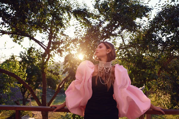 Güzel bir kadın lavanta tarlasında gün batımında siyah ve pembe elbiseler içinde dinleniyor. Çiçek tarlasındaki sarışın kadın. Provence.