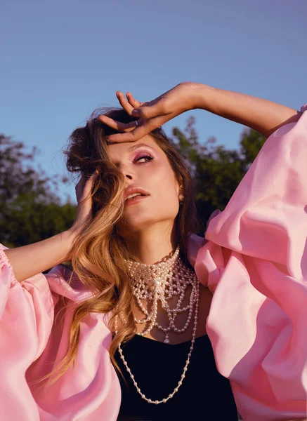 Güzel bir kadın lavanta tarlasında gün batımında siyah ve pembe elbiseler içinde dinleniyor. Çiçek tarlasındaki sarışın kadın. Provence.