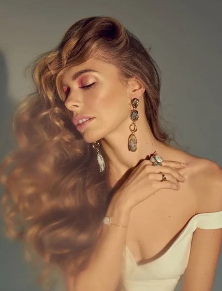 Mücevherlerinizi sunan genç ve çekici kadın modeller. Beyaz elbise giy. Çıplak makyaj, mükemmel cilt, uzun saç. Beyaz arkaplan.
