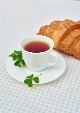 Masada beyaz arka planda papatya çayı ve taze kruvasan olsun. Bahar kahvaltısı kavramsal kompozisyonu