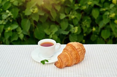Masada beyaz arka planda papatya çayı ve taze kruvasan olsun. Bahar kahvaltısı kavramsal kompozisyonu