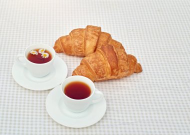 Masada beyaz arka planda papatya çayı ve taze kruvasan olsun. Bahar kahvaltısı kavramsal kompozisyonu