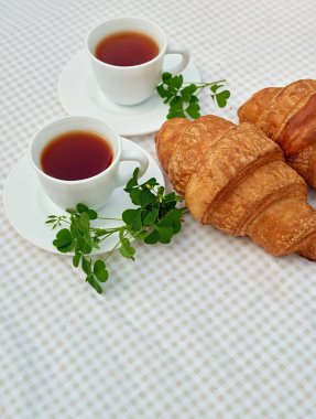 Masada beyaz arka planda papatya çayı ve taze kruvasan olsun. Bahar kahvaltısı kavramsal kompozisyonu