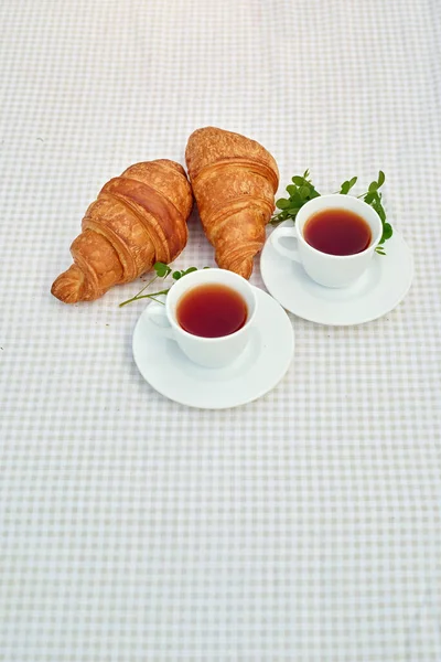 Twee Kopjes Zwarte Thee Met Kamille Verse Croissants Tafel Tegen — Stockfoto