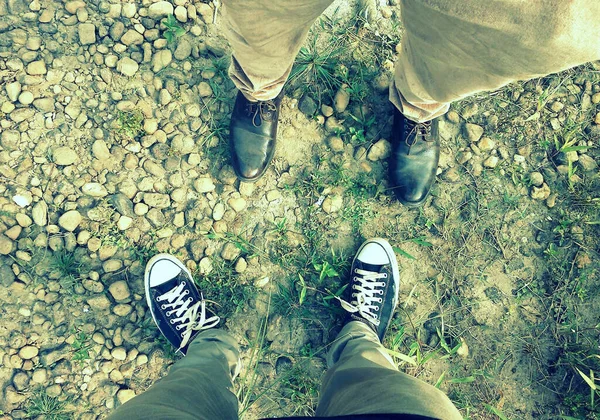 Legs of two friends standing face to face in the ground