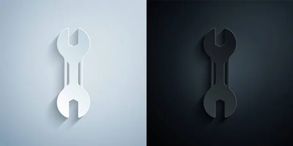 Иконка гаечного ключа, вырезанная бумагой, выделена на сером и черном фоне. Инструмент для ремонта ключей. Символ служебного инструмента. Бумажный стиль. Вектор — стоковый вектор