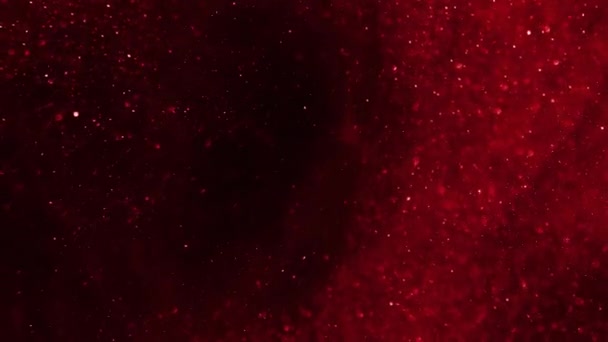 Red glitter moving against a dark background. — Stock video