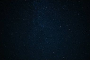 The blue night sky covered with bright stars photographed on a long exposure. Fantastic background