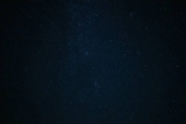 The blue night sky covered with bright stars photographed on a long exposure. Fantastic background