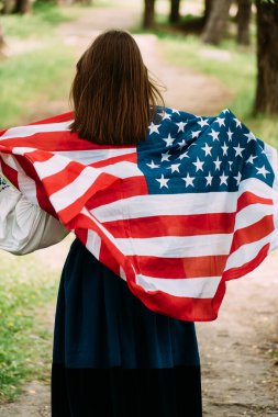 Yaz parkında Amerikan bayrağıyla poz veren bir kadın. ABD 'nin bağımsızlık gününü kutlayan pozitif kız.