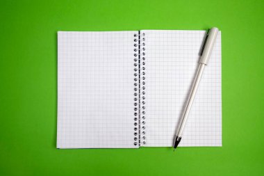 Yeşil arkaplan üzerinde açık kare defter ve kalem, boş alan, metin için boşluk, notlar