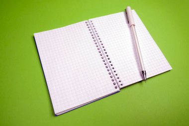 Yeşil arkaplan üzerinde açık kare defter ve kalem, boş alan, metin için boşluk, notlar